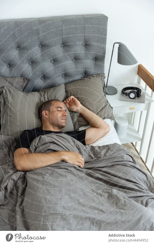 Man sleeping in comfortable bed at home man bedroom morning lying peaceful asleep male rest blanket relax pillow harmony duvet early quiet tranquil calm dream