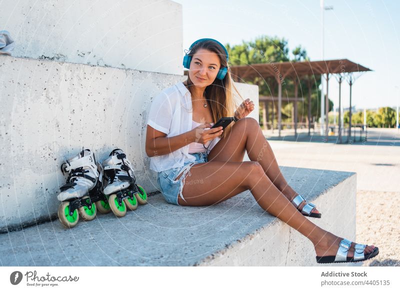 Smiling woman browsing smartphone and using headphones on the street city summer moment female happy cheerful text message mobile device smile cellphone gadget