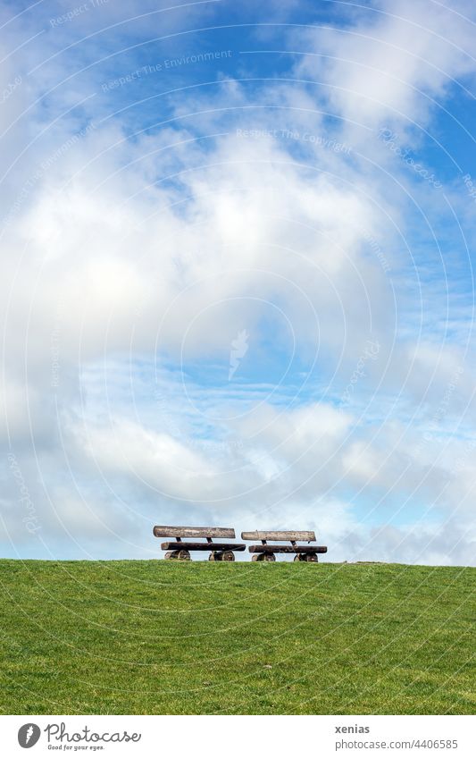 Standing two benches on the green dike under blue sky with clouds - a  Royalty Free Stock Photo from Photocase