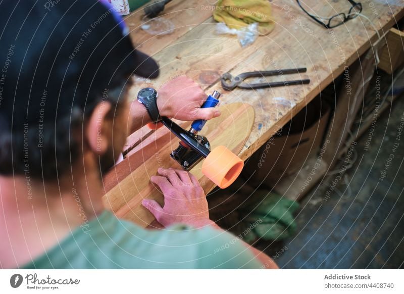 Focused artisan making skateboard in light workshop wheel attach focus professional handmade talent man make woodwork attentive skill carpenter workbench
