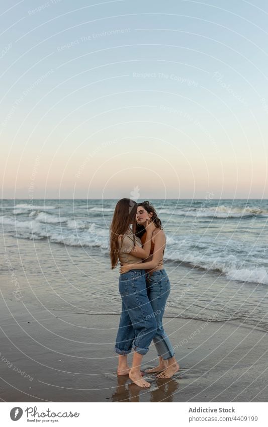 Lesbian couple kissing on beach women lesbian sea sundown hug love date female girlfriend romantic together sunset coast embrace relationship vacation summer