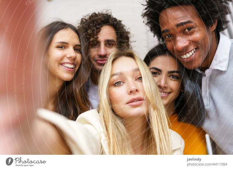 Multi-ethnic group of friends taking a selfie together while having fun outdoors. people smartphone multiracial multi-ethnic russian blonde girl caucasian