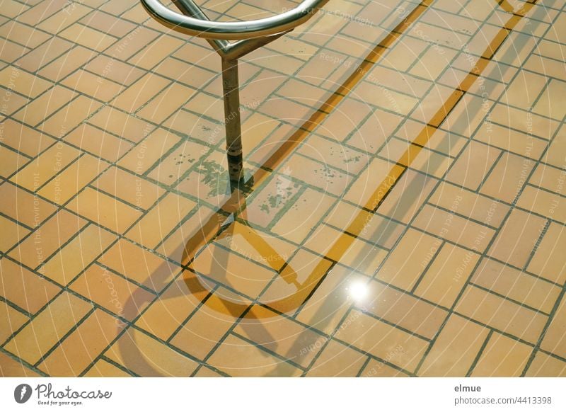 Partial view of a beige tiled Kneipp pool with metal handrail in the sunshine / treading water Kneipp basin Water Metabolic stimulation salubriously Metal