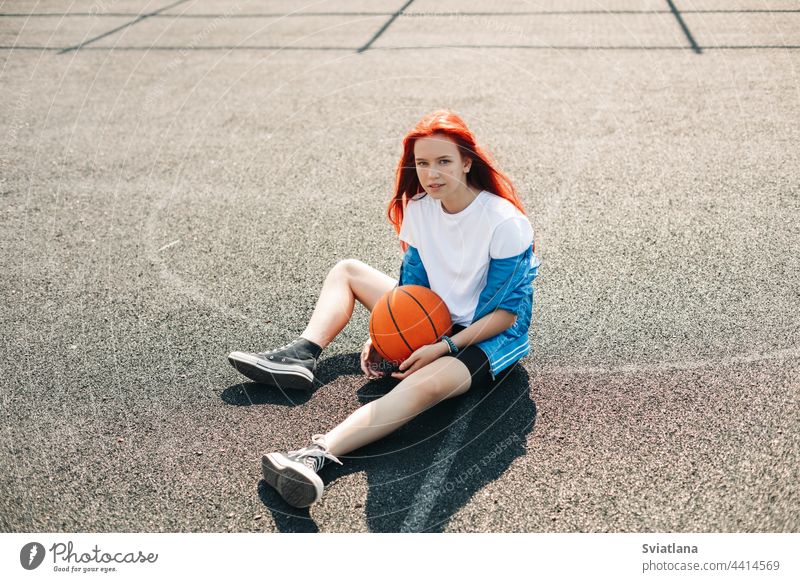 Girl athlete, summer city. Resting after playing sports on street