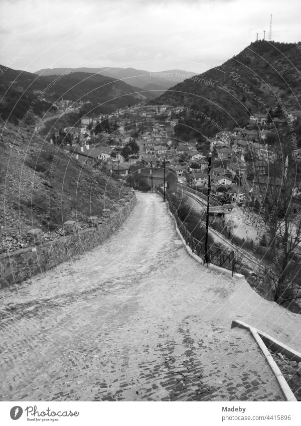 Road downhill into the valley between high mountains in the town of Göynük in the province of Bolu in Turkey, photographed in classic black and white Province