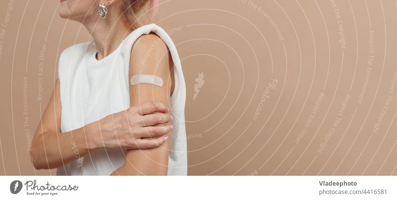 Young hipster woman with band aid after coronavirus Covid-19 vaccine injection. Covid vaccination concept, plain color background covid arm young showing