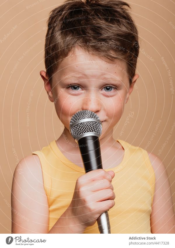 Preteen boy singing in microphone in studio child entertain cool singer style trendy music contemporary song audio sound perform kid modern playful childhood