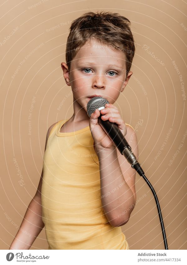 Preteen boy singing in microphone in studio child entertain cool singer style trendy music contemporary song audio sound perform kid modern playful childhood