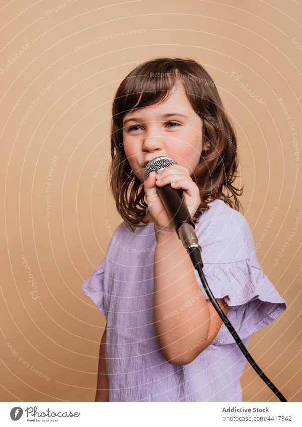 Funny child singing in mic in studio microphone girl funny make face comic grimace song entertain face expression cool singer style trendy music contemporary