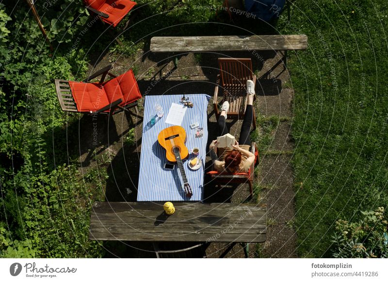 Coffee break in the garden with guitar and book Leisure and hobbies Guitar tool Table Garden table Woman person Reading Human being Break Literature