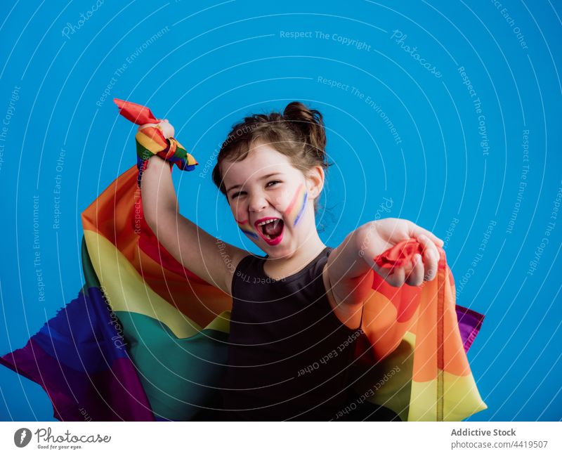 Cheerful girl holding multicolored flag kid child colorful childhood little smile vivid cute toothy smile vibrant stripe innocent adorable delight creative