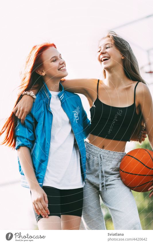 Two funny girls with a basketball hug each other after a game or workout. The concept of sports and friendship court holding best friends basketball court