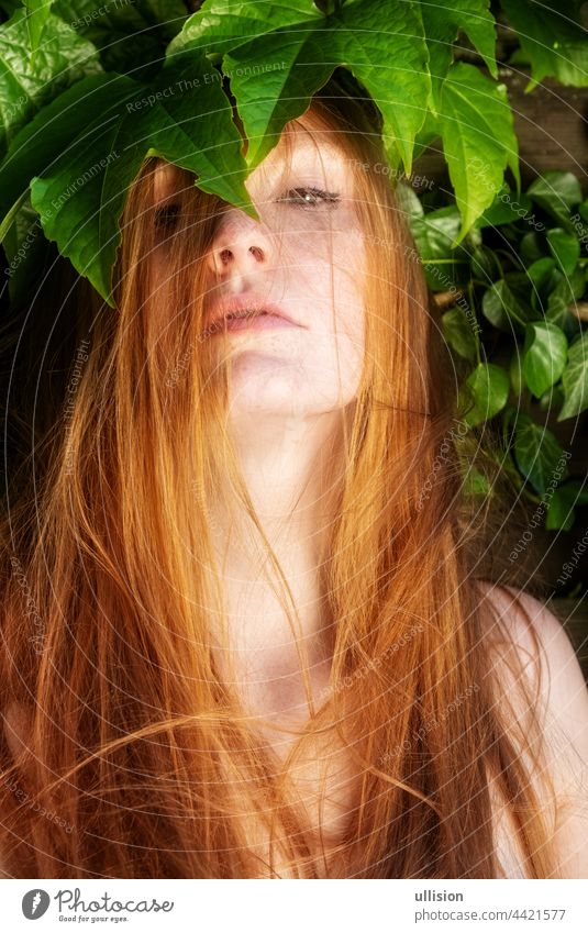 Portrait of young sexy woman redhead ginger with curly red hair thoughtful, stands before under wild wine Girl red-haired vogue portrait freckles expression