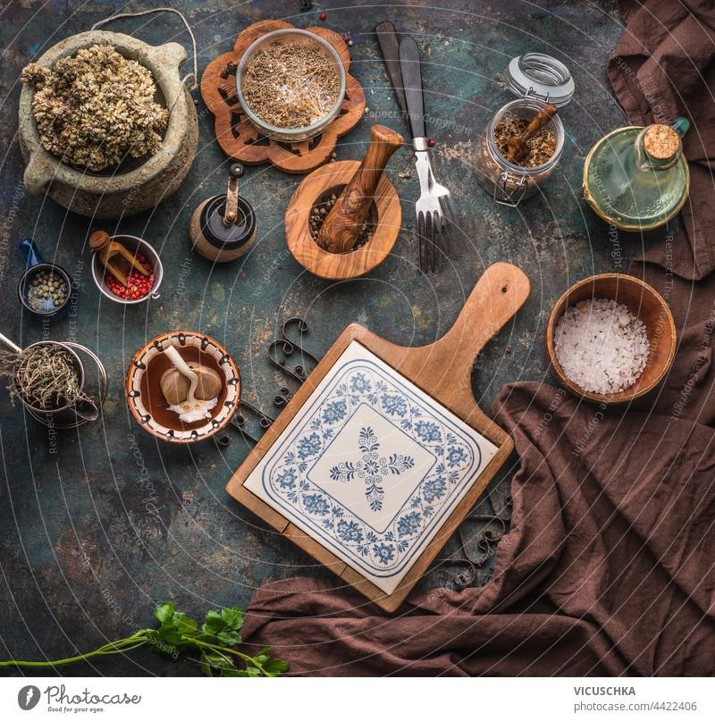 Various rustic aged kitchen utensils on dark table background with chopping board, forks and dried condiments. Top view various top view cooking cuisine food