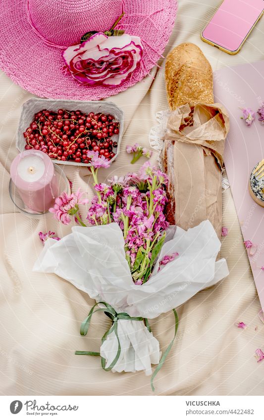 Pink hat with baguette , bunch of flowers and fruits on picnic blanket. Top view. Outdoor. pink top view outdoor outside tablecloth beautiful bread lunch