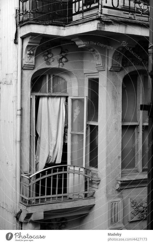 Open window with improvised curtain and small balcony of an old house in the alleys of Taksim in Istanbul on the Bosporus in Turkey, photographed in classic black and white
