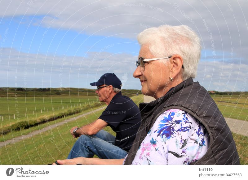 Senior couple sitting on the dike watching the birds vacation Relaxation North Sea blue sky with clouds Wangerooge Island Nature senior citizens Couple