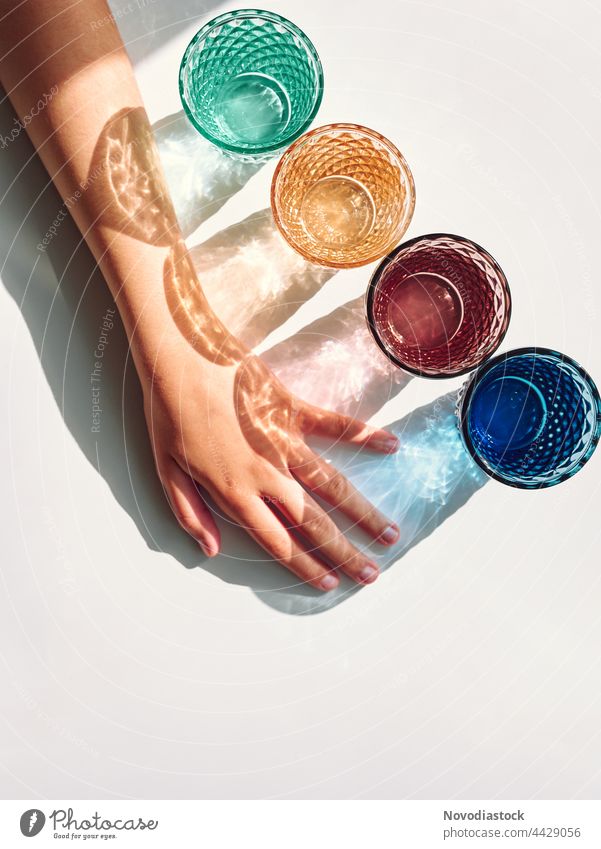Colorful glasses with shadows and a girl's arm isolated on a white background Drinking Beverage Colour photo Interior shot Glass Drinking water Day Water Fluid