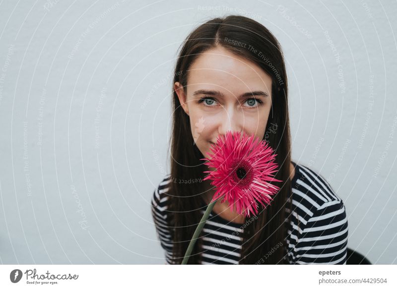 Smiling young woman hides behind a flower that partially covers her face Bright brown hair Easygoing Copy Space Face Flower kind Gerbera green eyes hiding