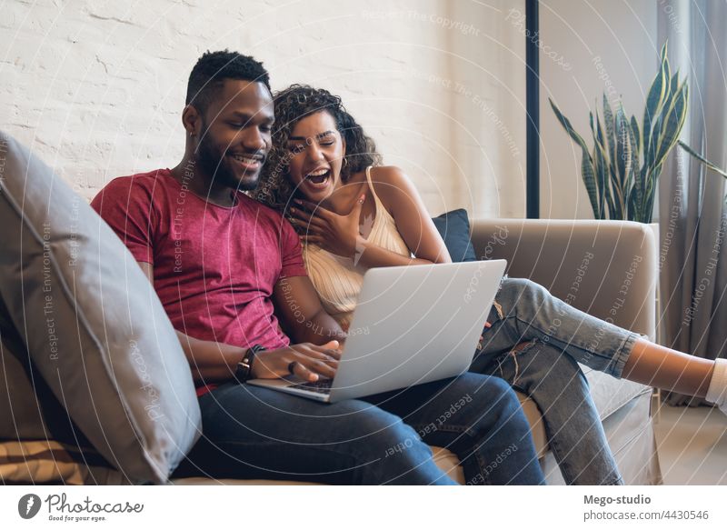 Couple using a laptop while sitting on a couch at home. couple man woman two lifestyle together sofa relationship boyfriend girlfriend modern male female