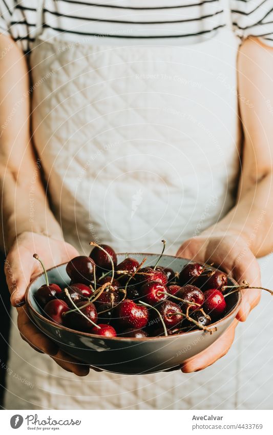 Old waitress offers and holds a bunch of cherry in a dish, fruits, healthy life, good eating, mediterranean concepts, copy space, vertical image artist