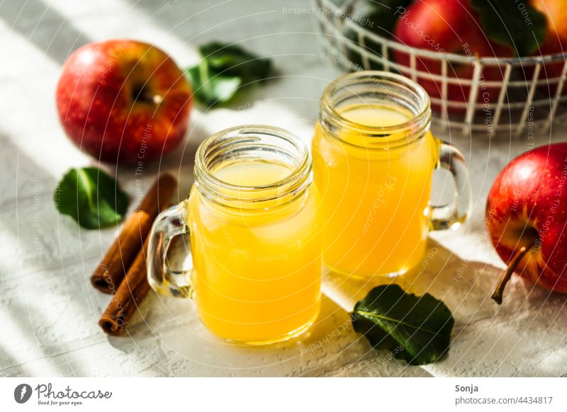 Fresh apple juice in two glasses and red apples on a white table Apple Juice Glass Red Beverage Cold drink Breakfast Delicious Drinking Interior shot Lemonade