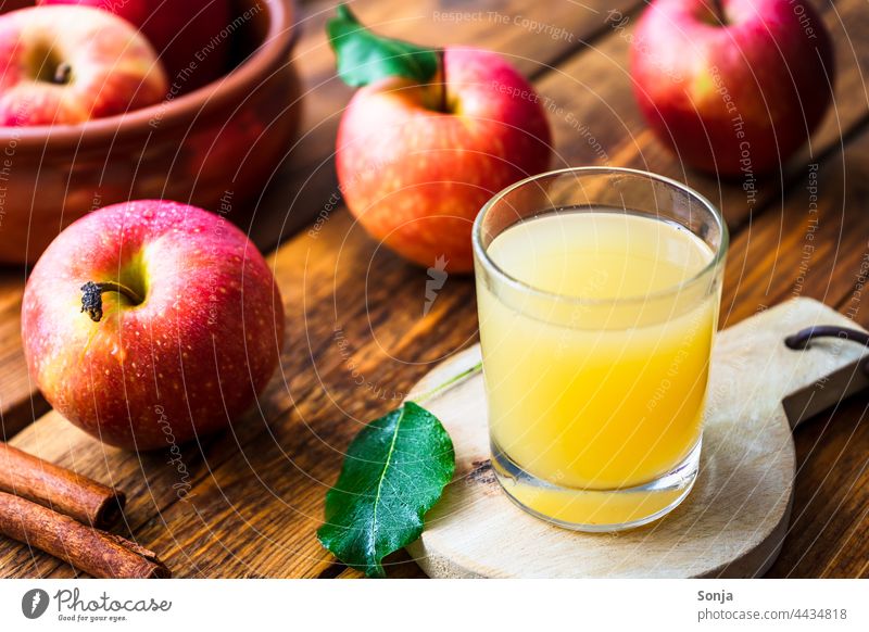 Fresh apple juice in a glass and red apples on a wooden table Apple juice drinking glass Wooden table Autumn Delicious Organic produce Interior shot