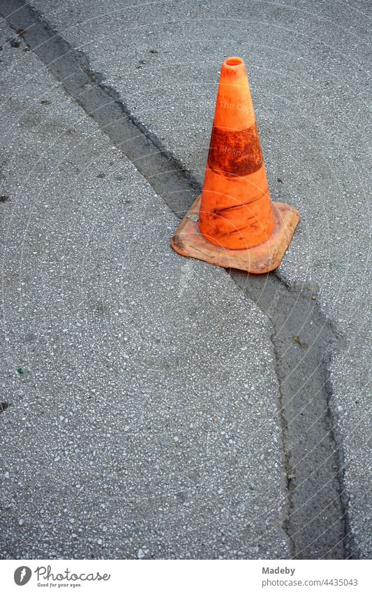 Old Lübeck hat in bright orange on a repaired grey road surface in Adapazari in the province of Sakarya in Turkey Skittle Traffic cone Street Transport