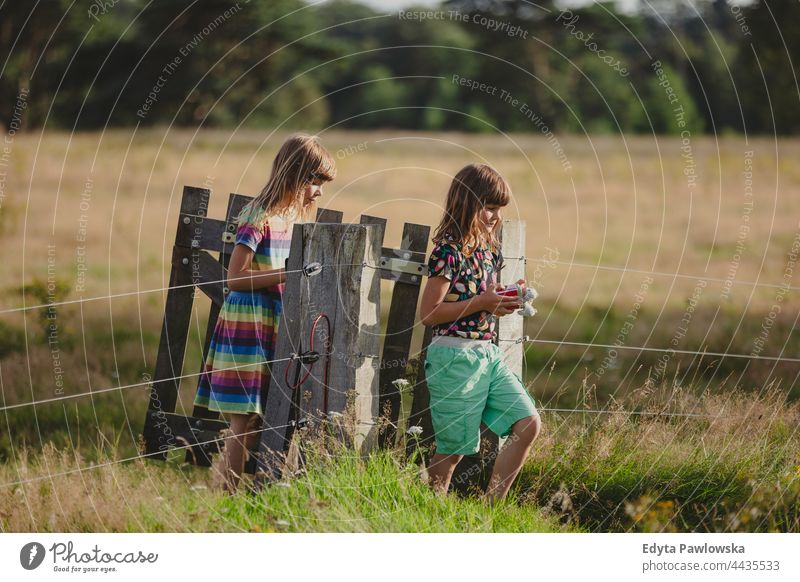 Children walking through a wooden gate in a field fence active activity adventure autumn child childhood children countryside enjoying family farm female forest