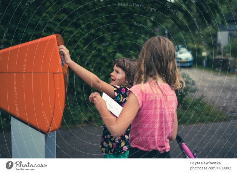 Children putting a postcard in the mailbox, Netherlands posting letter postbox sending letter friendship together vacation adventure summertime day enjoying
