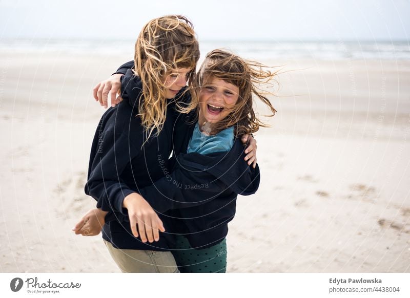 Two sisters playing on the beach friendship sisterhood love together sea sand sky water vacation travel active adventure summertime day freedom holiday enjoying