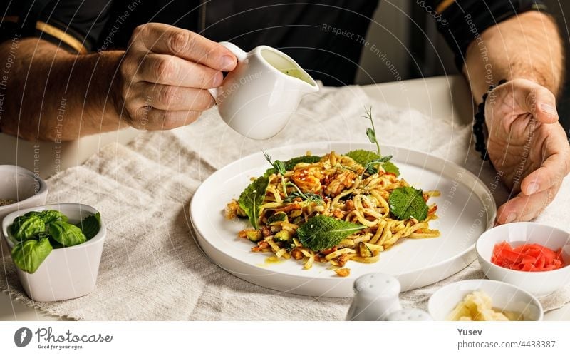 Spaghetti with seafood. The hands of the head chef prepares a traditional pasta with seafood. The cook pours the sauce over the dish. Restaurant serving dish. Mediterranean Kitchen Banner