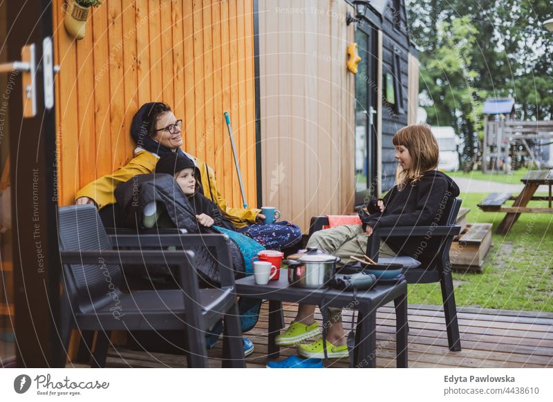 Mother and children talking in front of the wooden cabin at the campsite real people authentic mother parent together love house family kids camping field rural