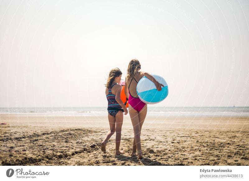 Two children on the beach with an inflatable ball real people authentic sea ocean sand sky water toy vacation travel active adventure summertime day freedom