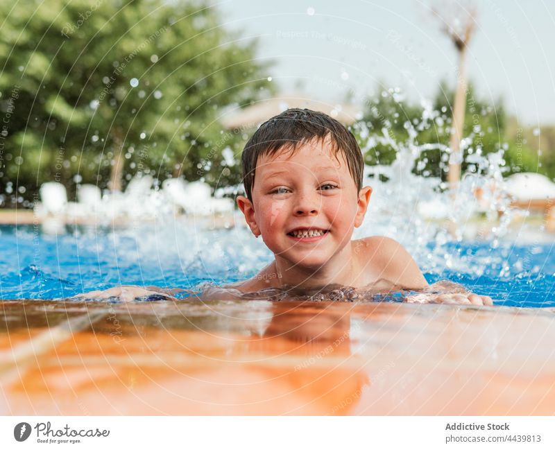 Cheerful boy in swimming pool in summer child poolside cheerful having fun water wet hair kid joy smile weekend happy enjoy pleasure vacation optimist charming