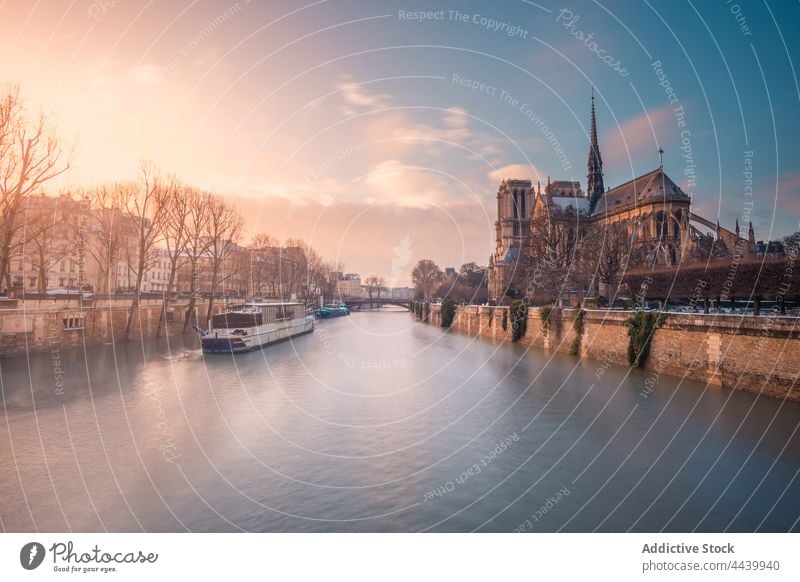 Motor ship on Seine river at sunset historic cathedral architecture landmark medieval sightseeing heritage catholic culture sundown religion facade city water