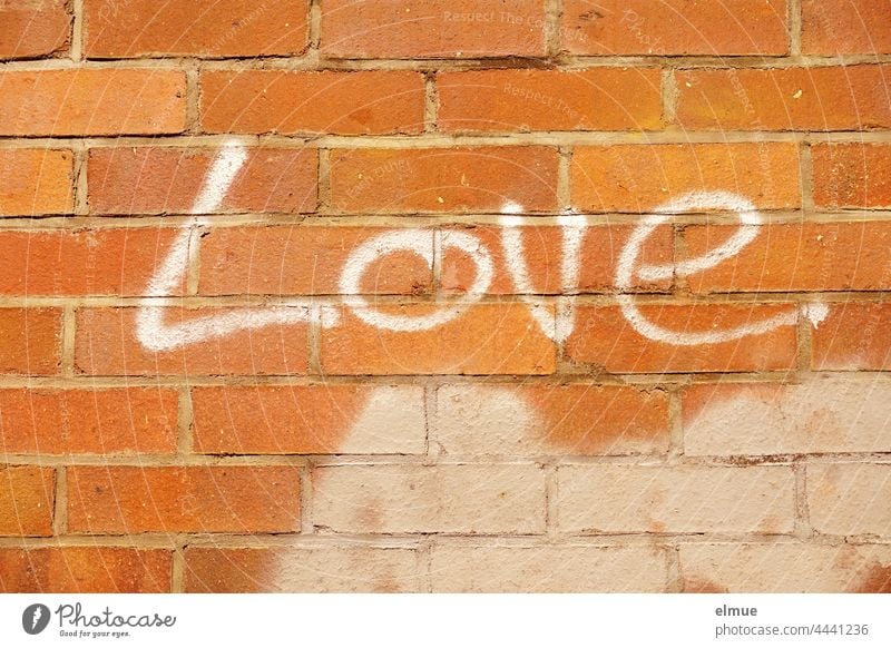 Love is written in white letters on the red brick wall / graffito Brick wall Graffito Graffiti writing spray Word English Declaration of love token of love