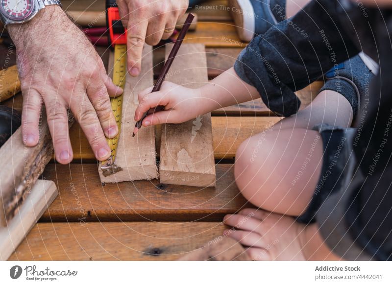 Crop father with son measuring wooden plank measure woodwork diy tape pencil handicraft help man precise boy interact tool childhood fatherhood spend time dad