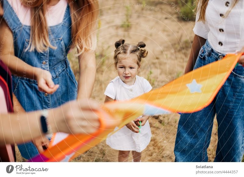 Close-up of a little girl watching her mother prepare a kite for launch mom baby launching childhood playing family woman relationship nature kid happy together