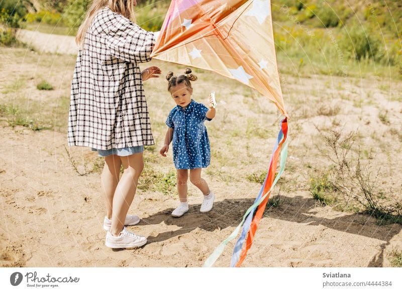 A charming little girl has fun and launches a kite together with her older sister family sisters outdoor green cute pretty best two caucasian summer cheerful