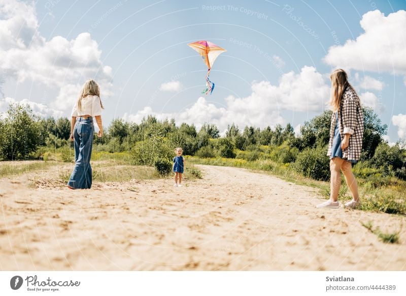 A mother flies a kite with her daughters during a family vacation in the country little girl sisters mom fun outdoor green cute pretty best two caucasian summer