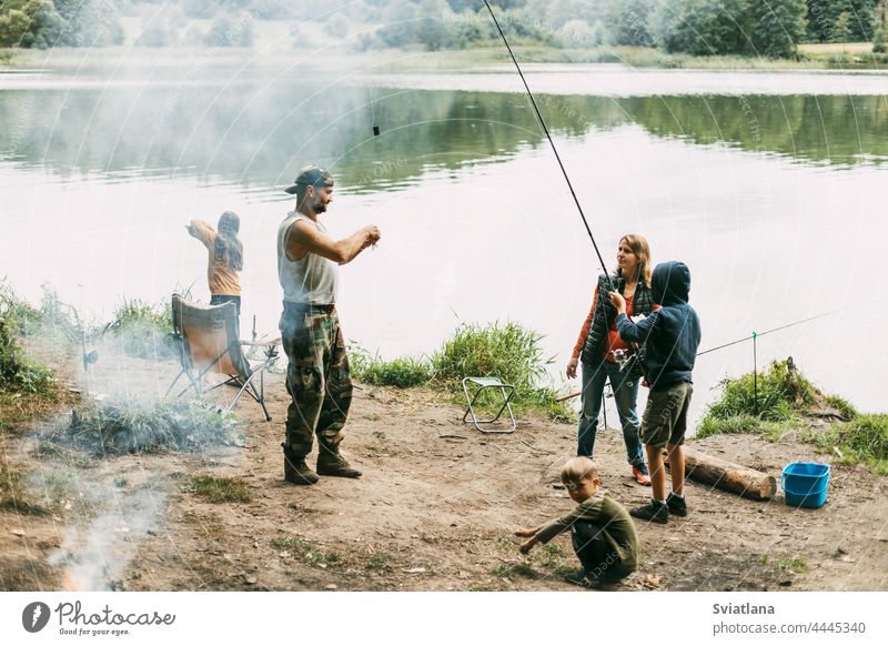 A happy family is fishing on the bank of a river or lake. Spending time together, family time, family vacation mom daughter son dad mother parenthood