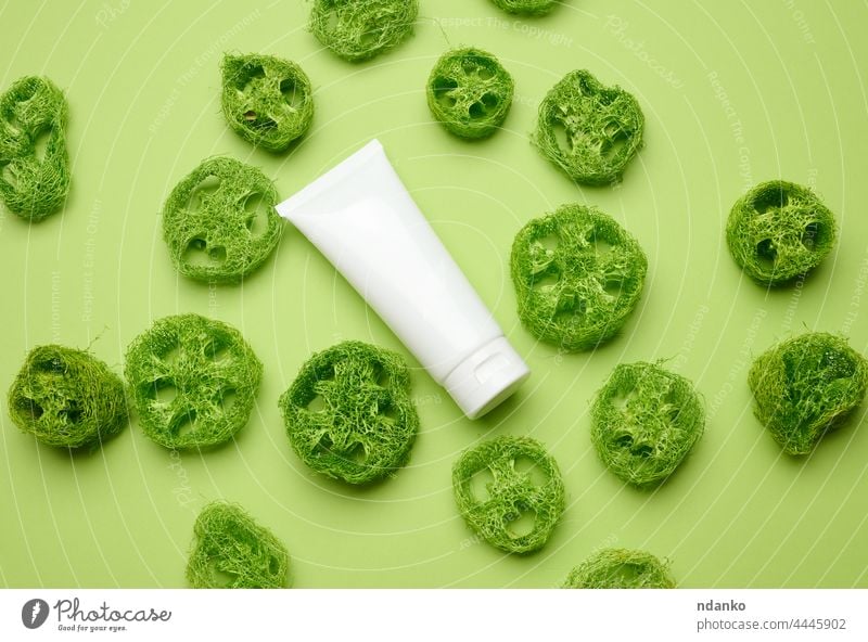 empty white plastic tubes for cosmetics on a green background. Packaging for cream, gel, serum, advertising and product promotion, top view loofah decor beauty