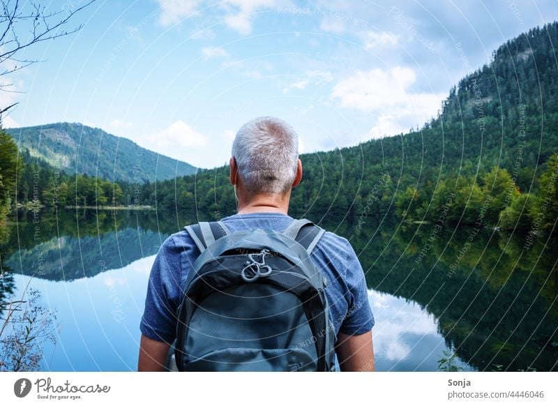 Man with a backpack stands by a lake and enjoys the view Backpack Hiking Rear view Lake Trip Tourism Vacation & Travel Freedom Senior citizen gray hair