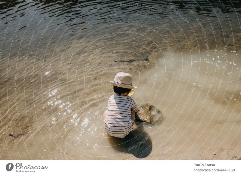 Rear view child with hat playing on the beach Child Playing Beach 1 - 3 years Caucasian Summer Sunlight Summer vacation Hat Authentic River River bank