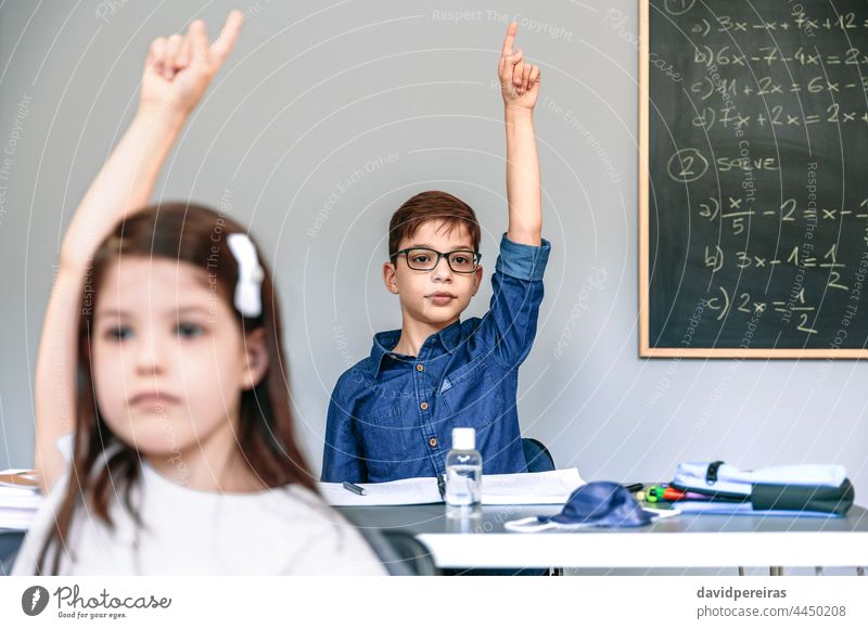 Students with mask on table raising hands at school new normal coronavirus student class participating safety people girl boy epidemic education classroom smart