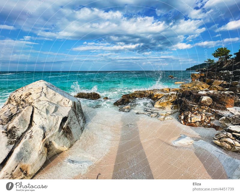 Rocks on the beach by the sea with light cloudy sky Beach Ocean Surf Sandy beach vacation coast Sky partly cloudy Blue White crest Nature Landscape Waves Water