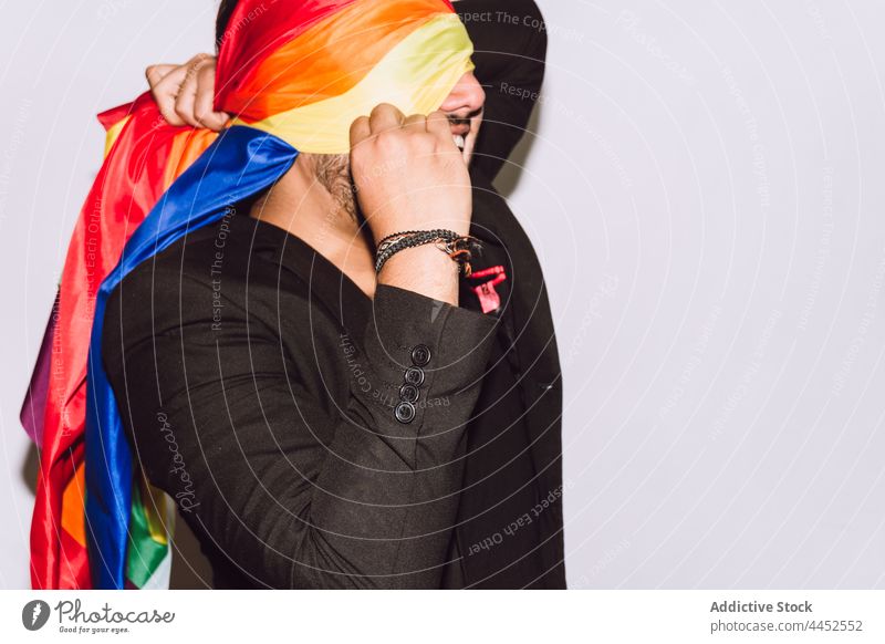 Gay man covering face with LGBT flag gay rainbow wrap pride symbol community respect homosexual male solidarity multicolored identity demonstrate right lgbtq