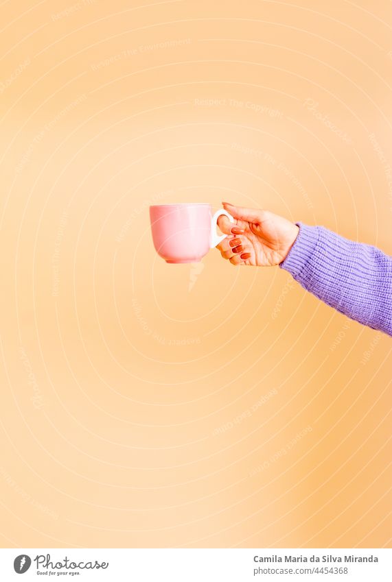 Closeup of female hands holding a light pink cup. Girl with beautiful nails. holding cup of tea or coffee. Studio photo. Photo for cropping. Empty. autumn