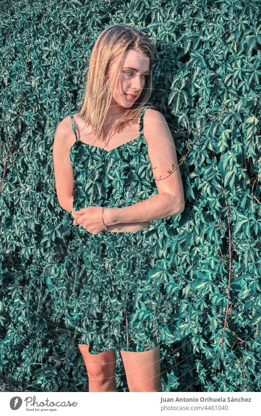 Blonde girl in a green leaves dress integrated into a nature background bizarre fresh glamour long hair floral magic people romantic plant sensual amazing style